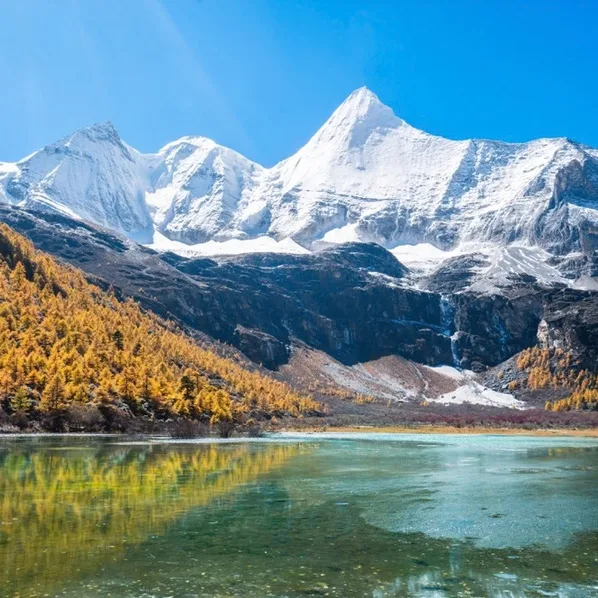 Snow-capped mountains above an autumn valley lake in western Sichuan
