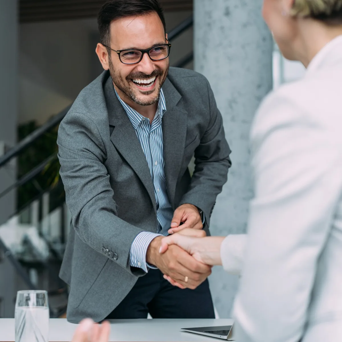 Two business partners shaking hands across a table